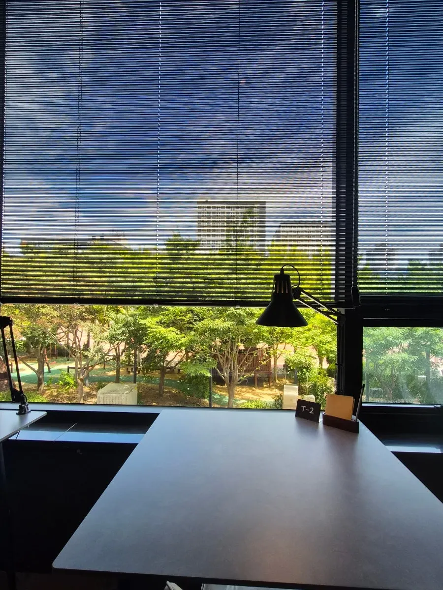 Seating by the floor-to-ceiling windows with blinds halfway down
