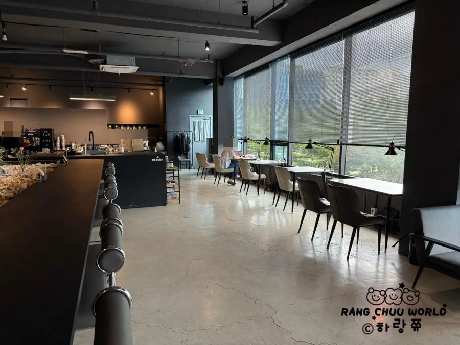 Interior kafe bertona hitam dan kelabu dengan meja besar di tengah