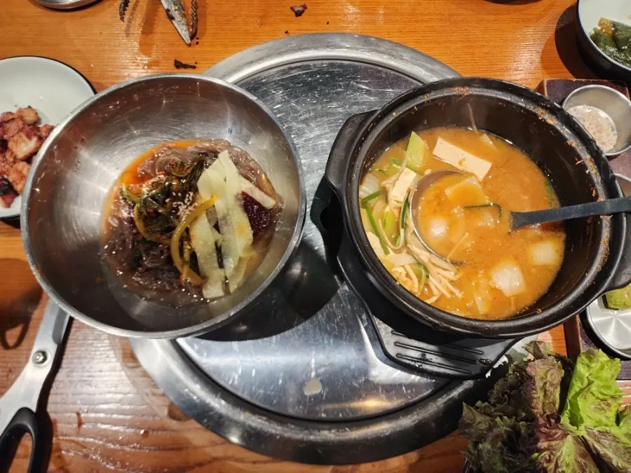 Lifting up a bite of bibim-naengmyeon noodles