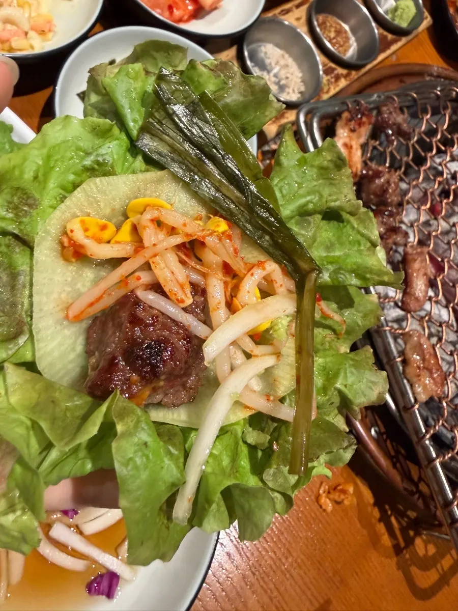 A wrapped piece of charcoal-grilled meat held up