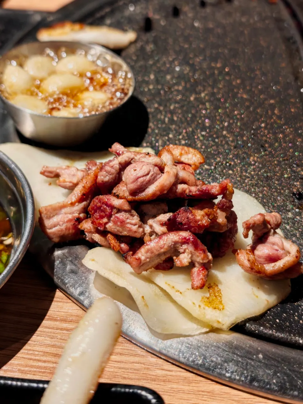 A well-grilled piece of raw duck picked up with chopsticks