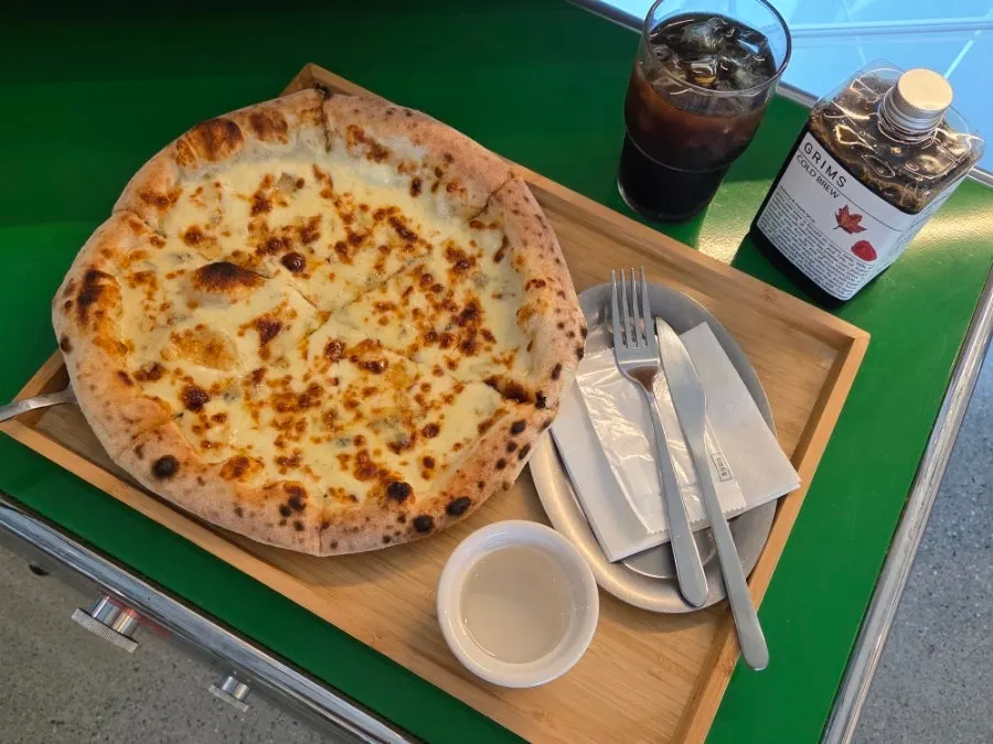 Pizza gorgonzola dan cold brew di atas meja