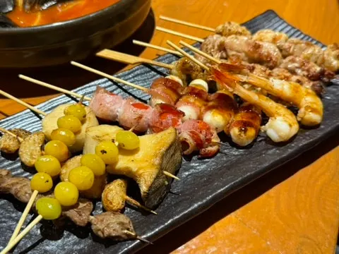 Skewers and grilled fish cooking over charcoal
