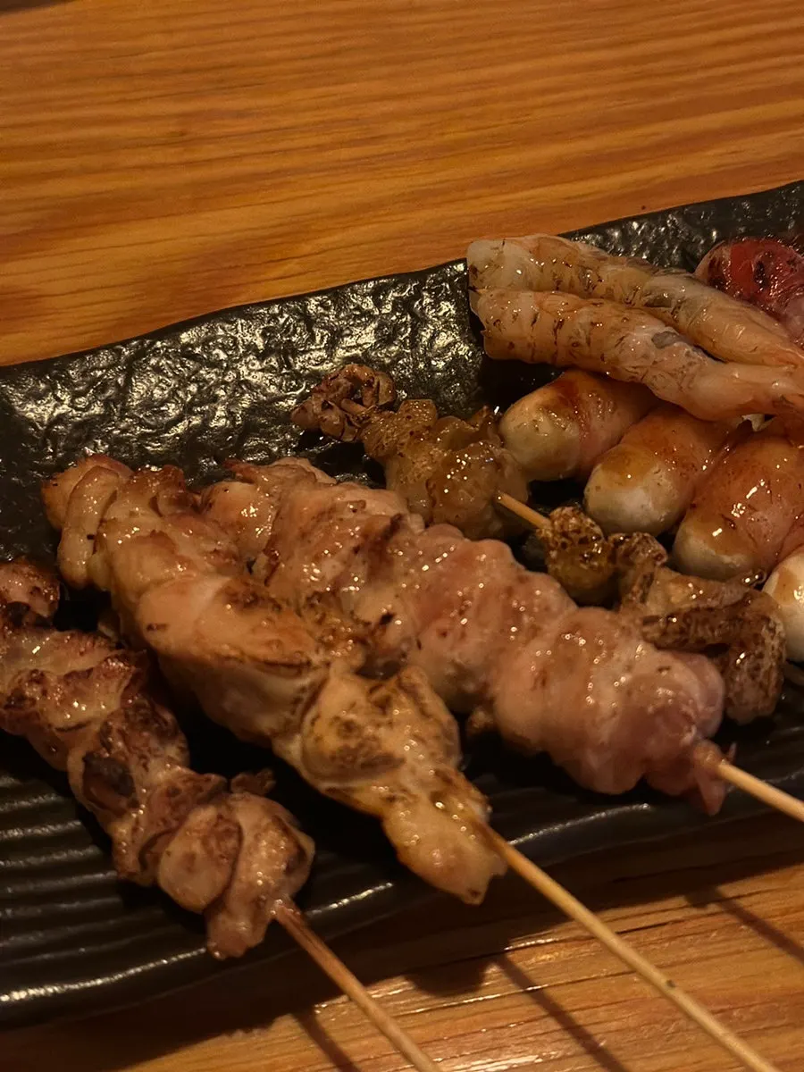 Mixed skewer platter showing bacon cheese rice cake and chicken skewers