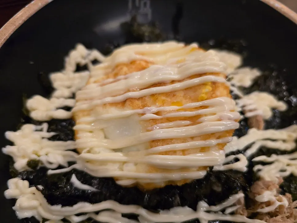 Close-up of soy egg rice drizzled with a wave of mayonnaise