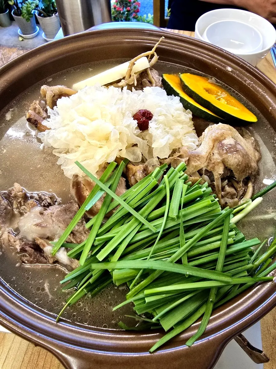 Ceramic pot of chicken baeksuk set over a burner