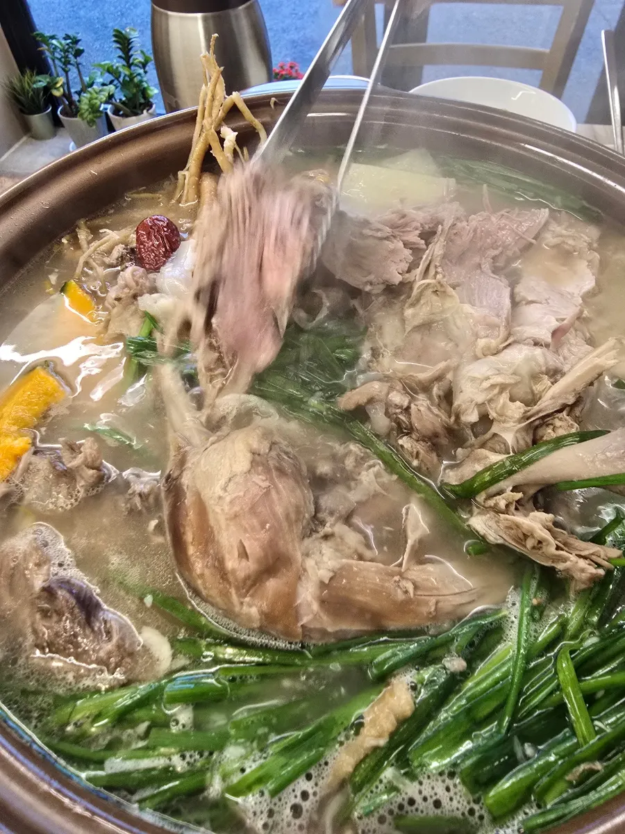 A spoonful of baeksuk broth with medicinal roots
