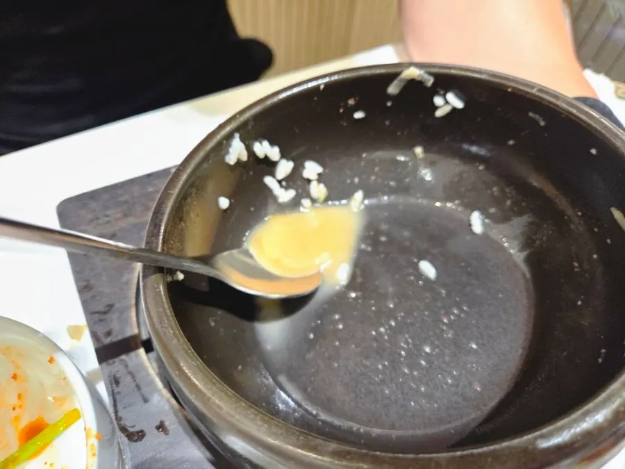 An emptied bowl of mixed pork gukbap with rice mixed in