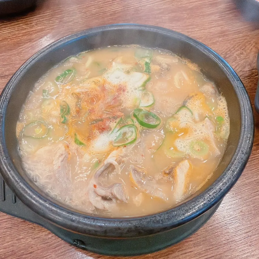 Stone bowl of spicy sundae gukbap topped with scallions and garnish