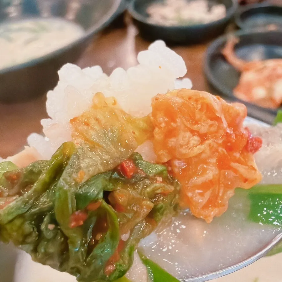 A spoonful of pork gukbap with onion and kimchi