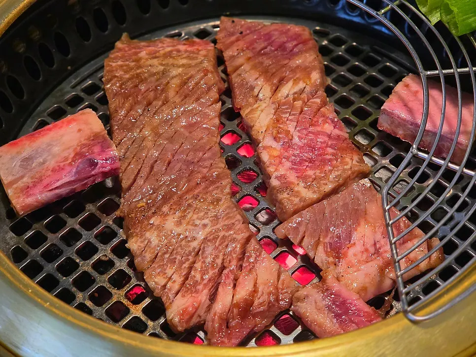 직원이 갈비를 구워주는 그릴링 서비스 장면