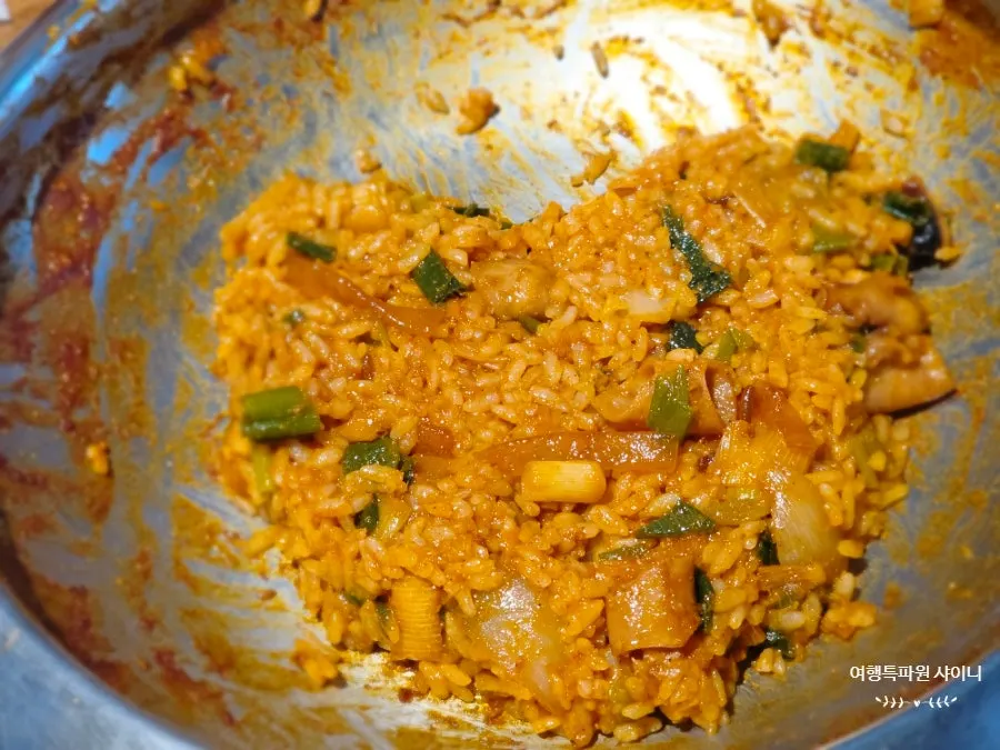 Self-made fried rice being stirred with seaweed flakes and sesame oil
