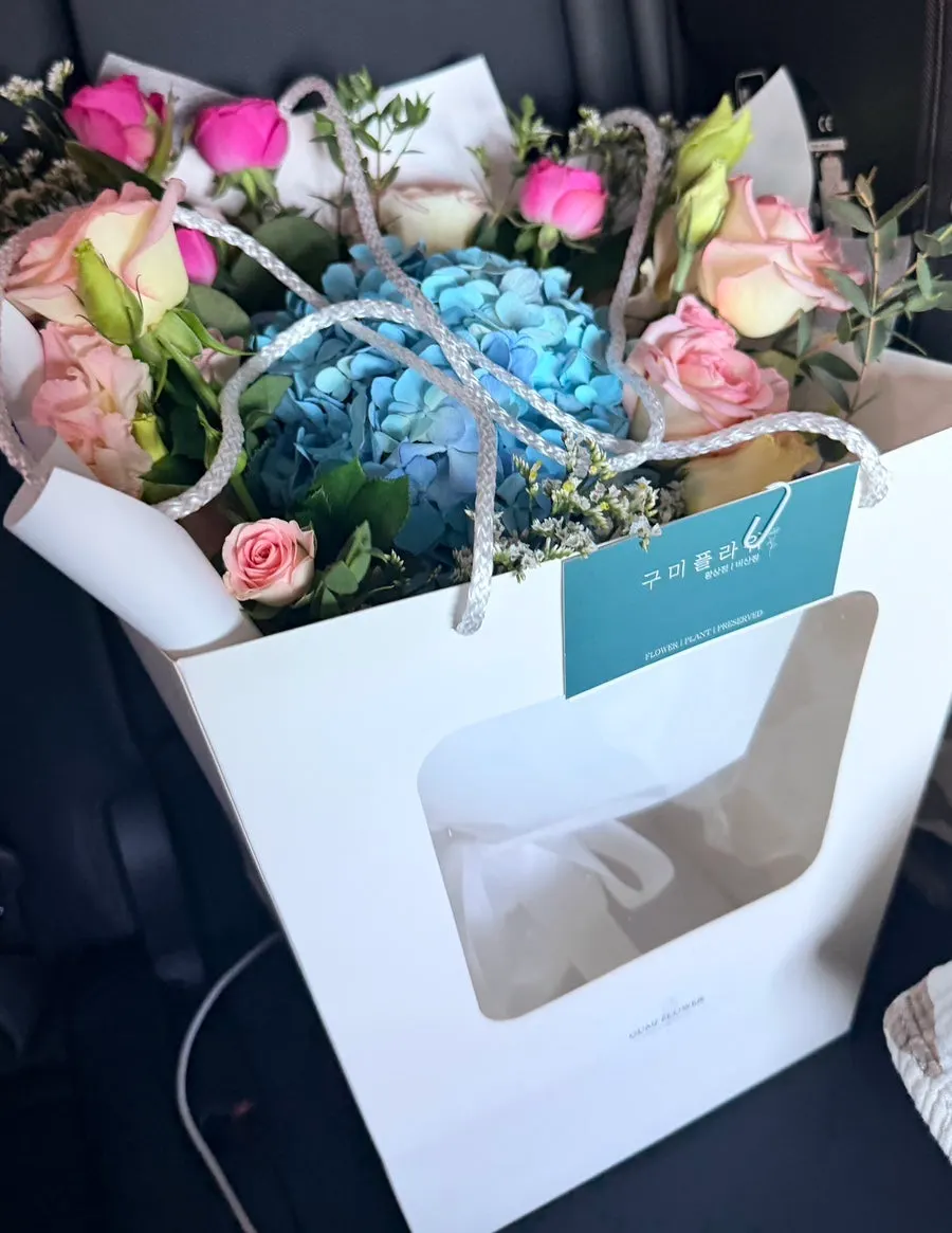 Bouquet packaged in a white shopping bag
