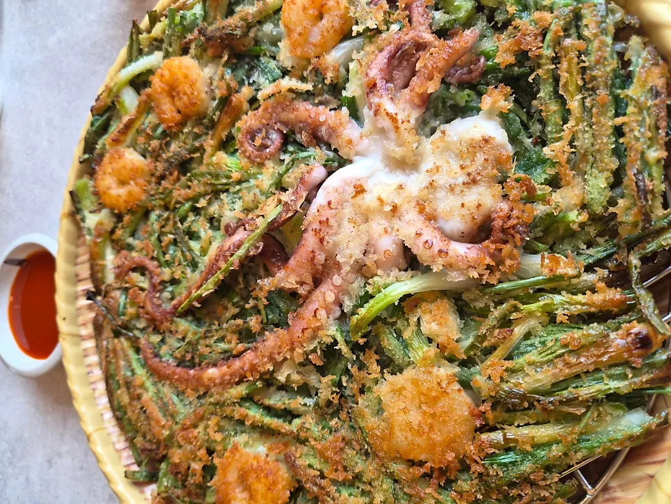 Seafood pancake sliced into bite-sized pieces dipped in chogochujang