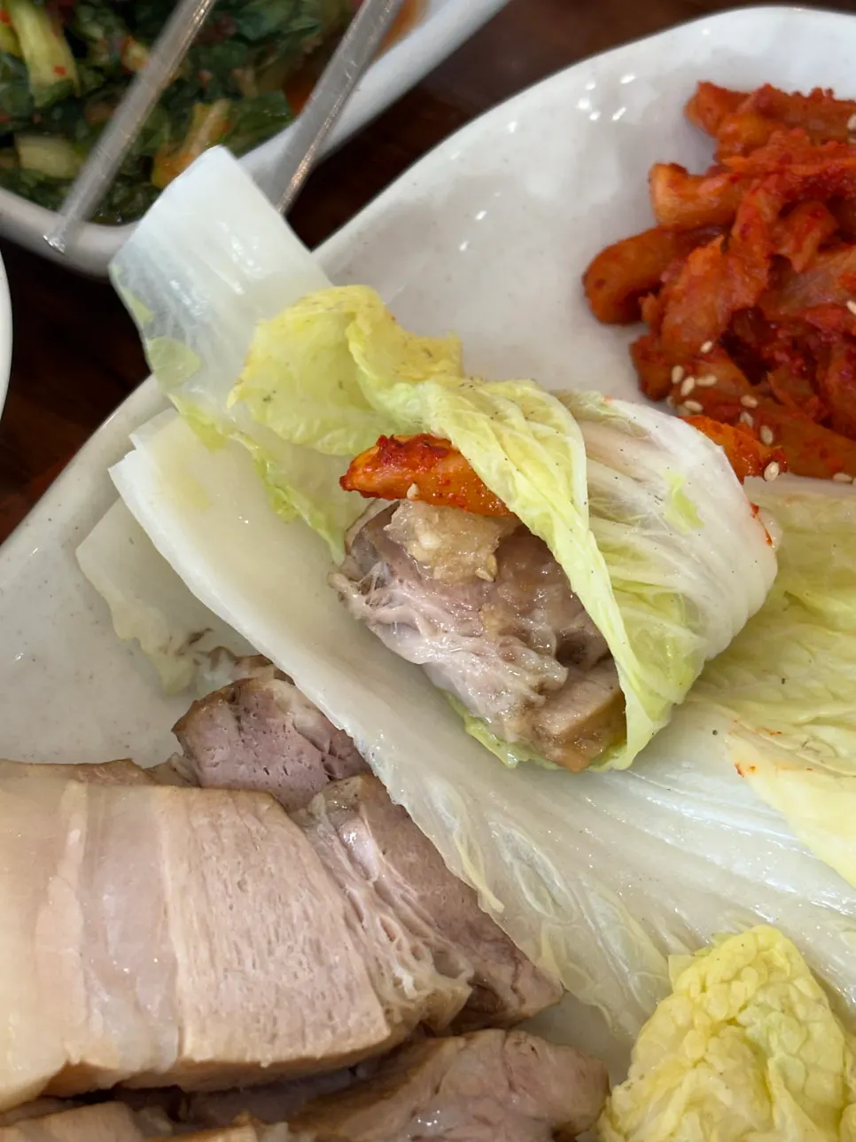 A piece of herbal medicinal bossam in a lettuce wrap