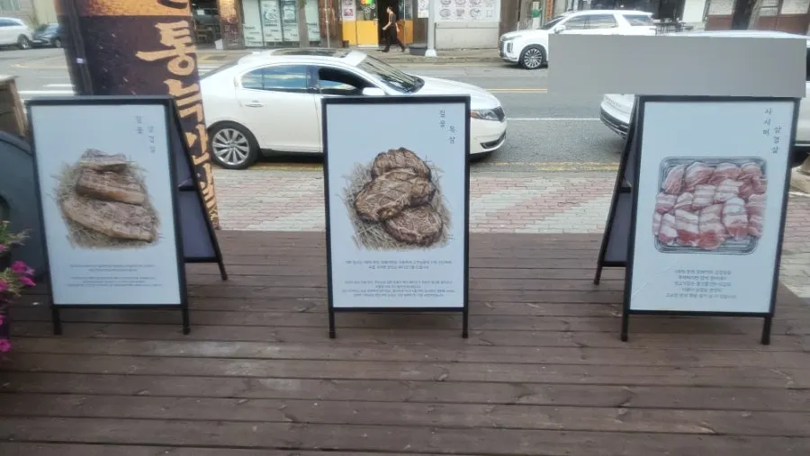 A banner with photos of meat displayed outside the restaurant