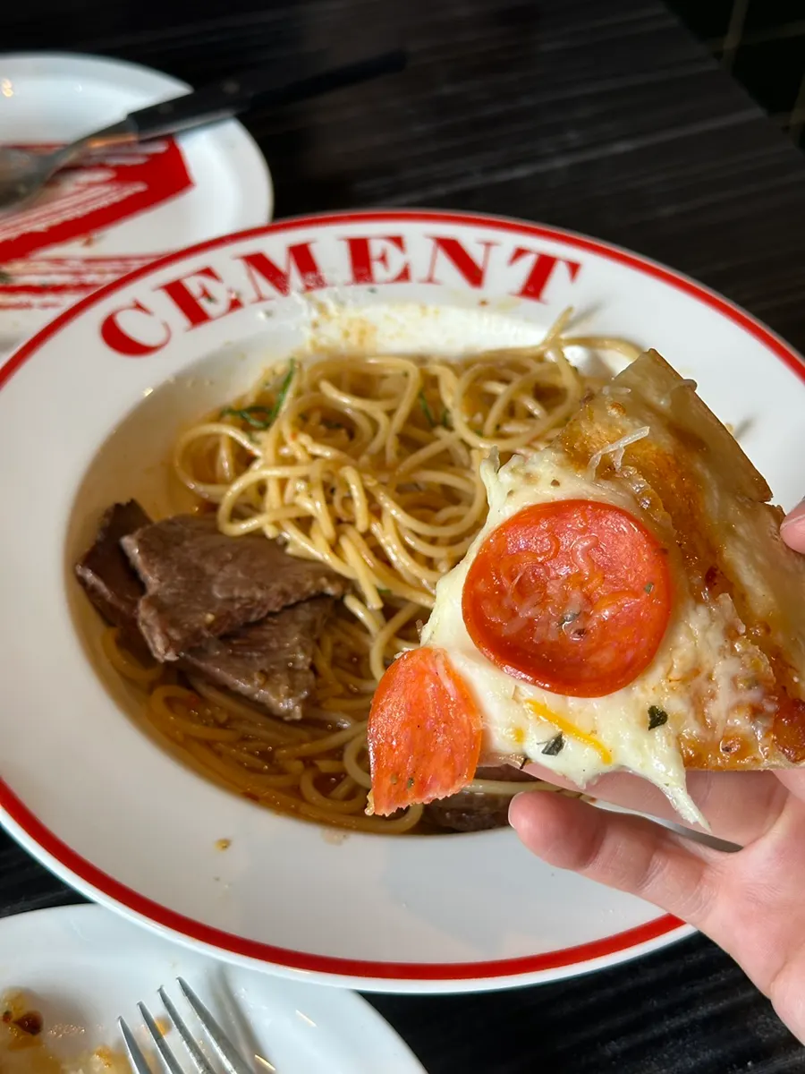 Eating a slice of pepperoni pizza together with the pasta
