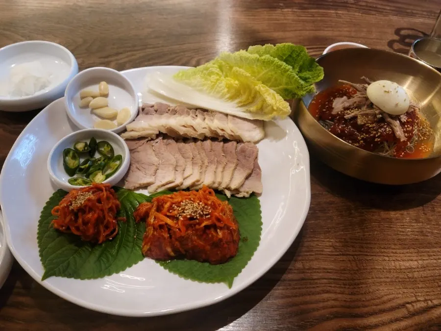 A bite of bossam paired with bibim naengmyeon