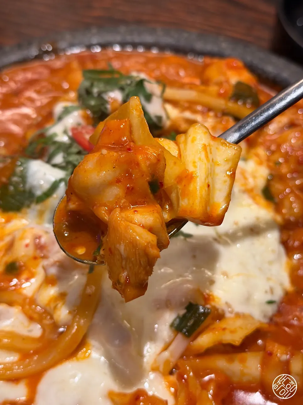 A bite of dakgalbi coated in melted cheese