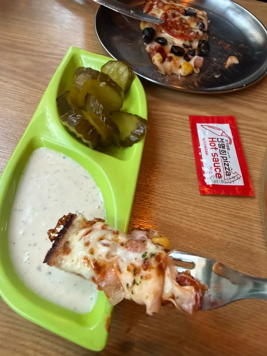 A pizza slice dipped in garlic sauce