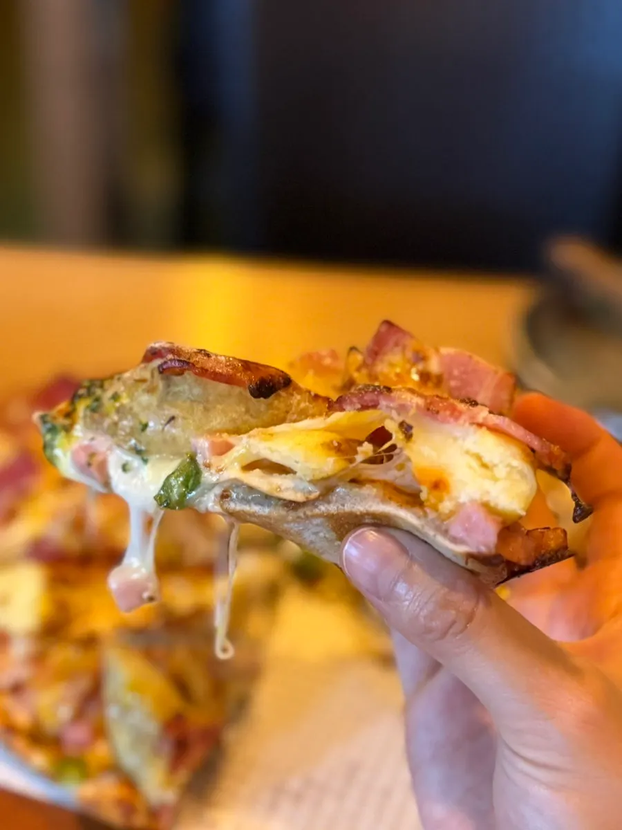A slice of pizza with stretchy melted cheese