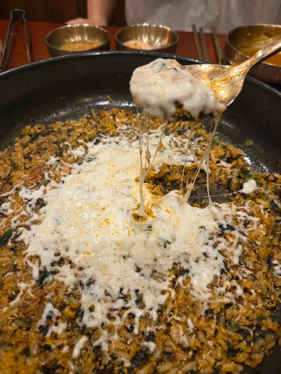 A spoonful of cheese fried rice with cheese stretching