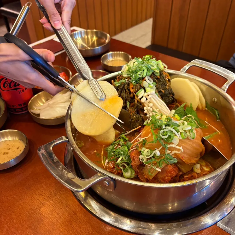 Aged kimchi and potatoes being cut fresh at the table
