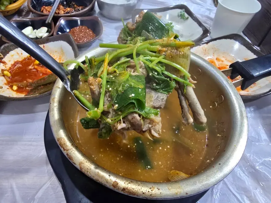 Pot of complimentary duck soup topped with minari