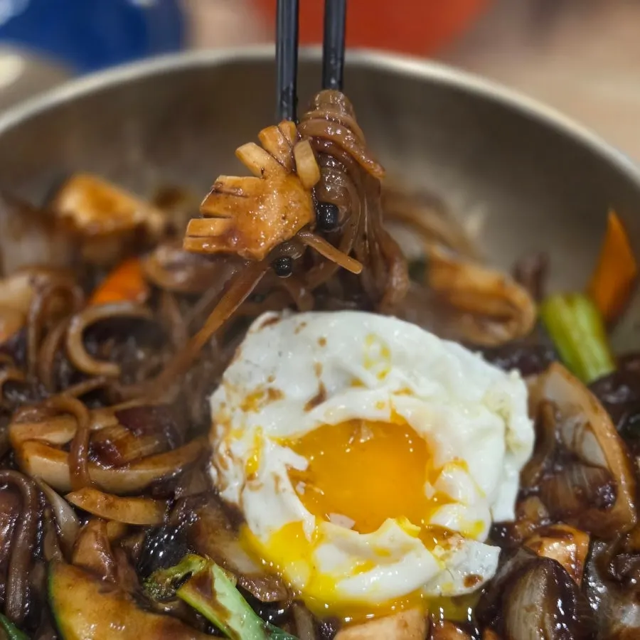 Platter jjajang noodles mixed with a broken egg yolk