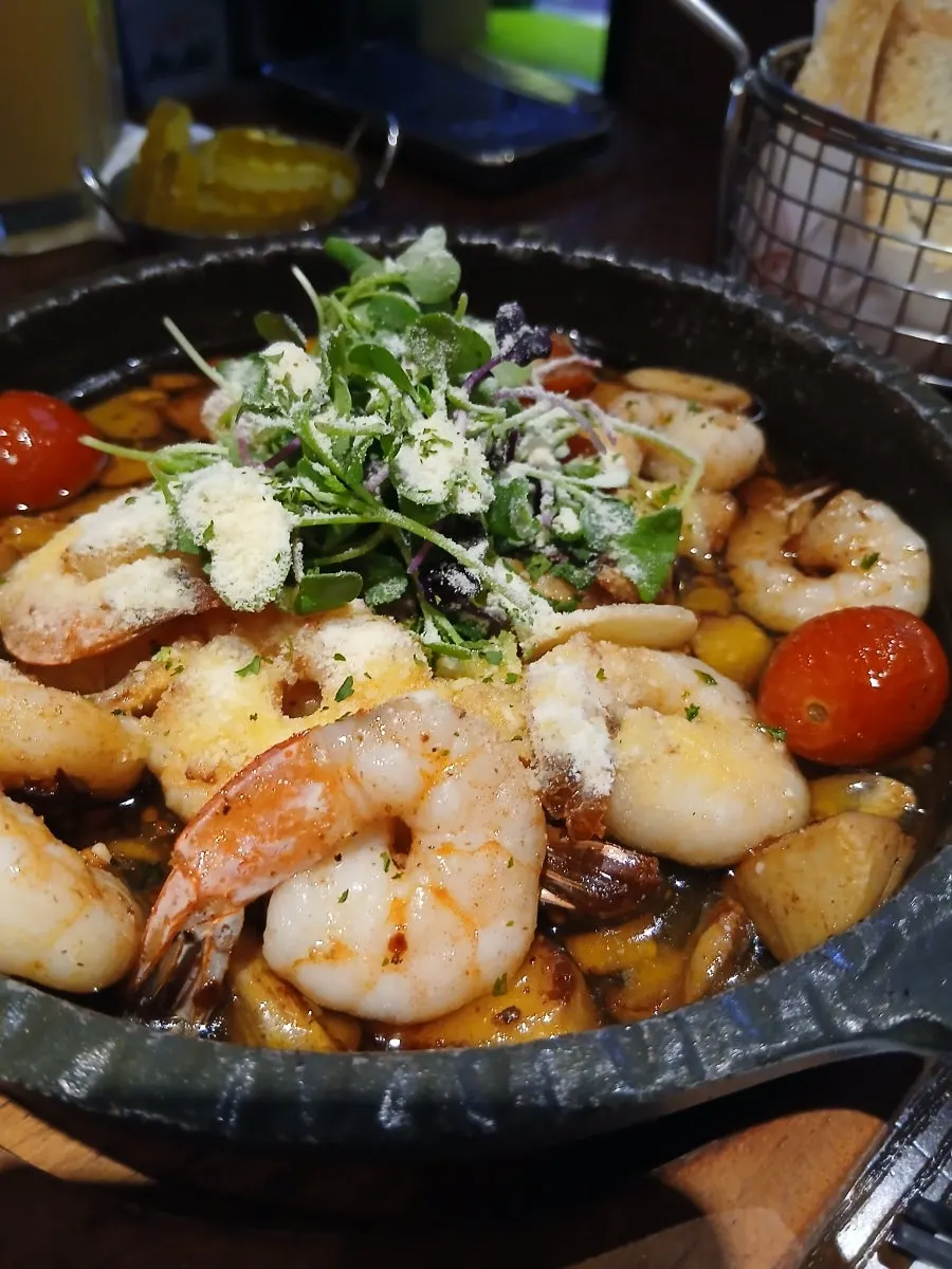 Gambas al ajillo bubbling in a cast-iron pan