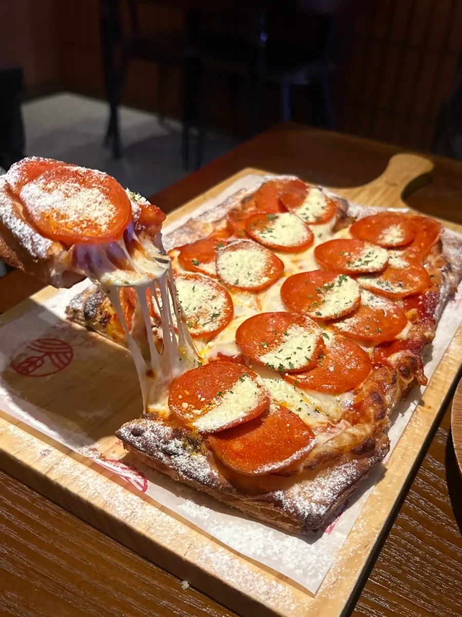 Picking up a light slice of pepperoni pizza