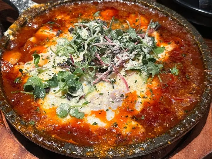 Close-up of egg-in-hell piled high with cheese