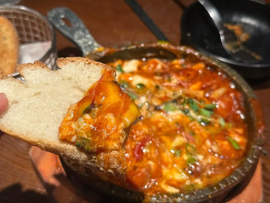 Dipping baguette into the egg-in-hell sauce