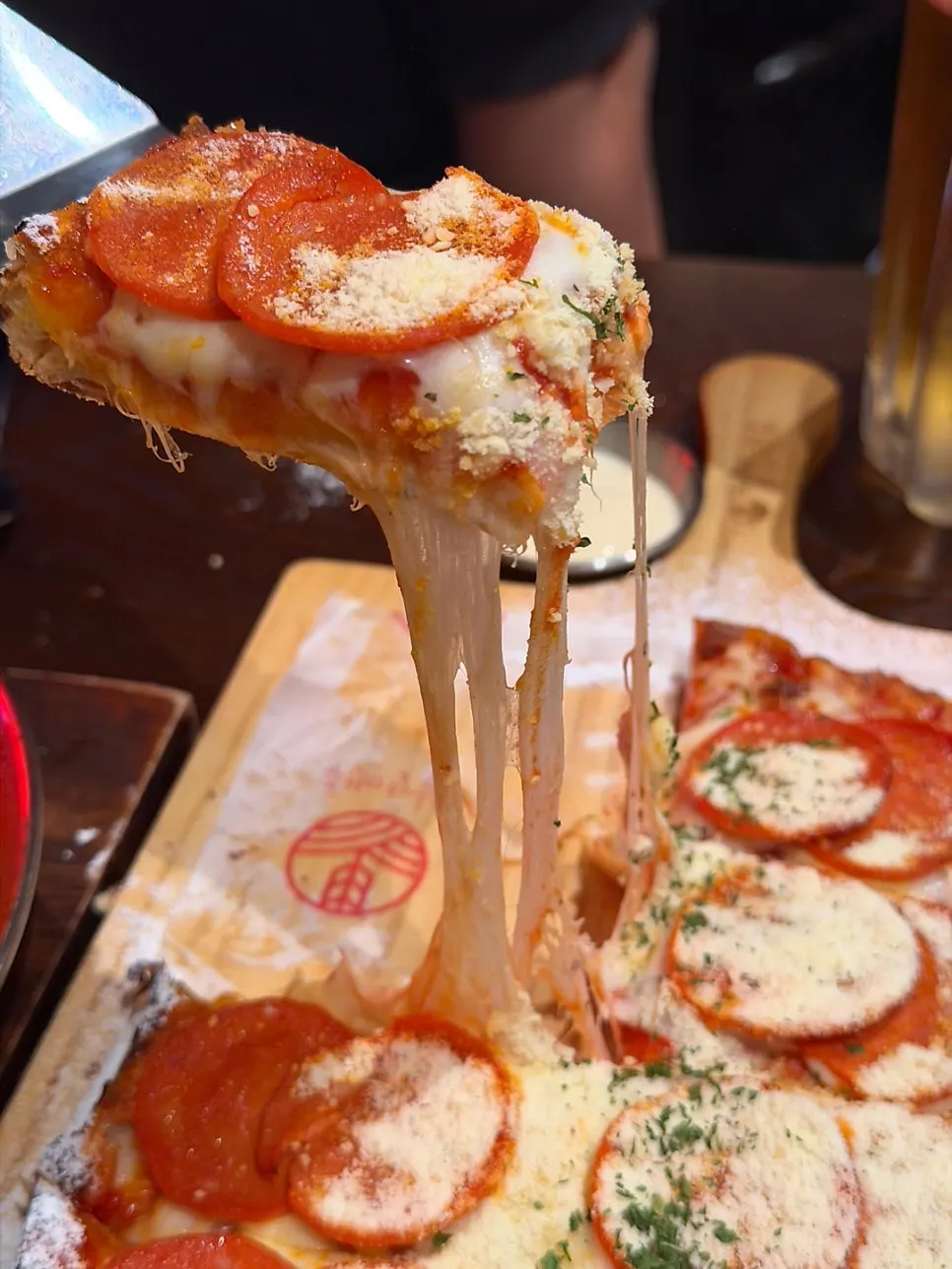 Square-dough pepperoni pizza on a wood tray