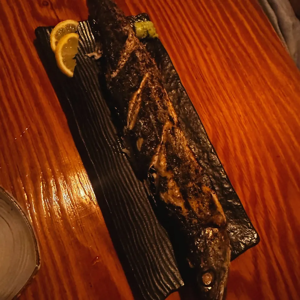 A large grilled mackerel spilling off the edges of the plate