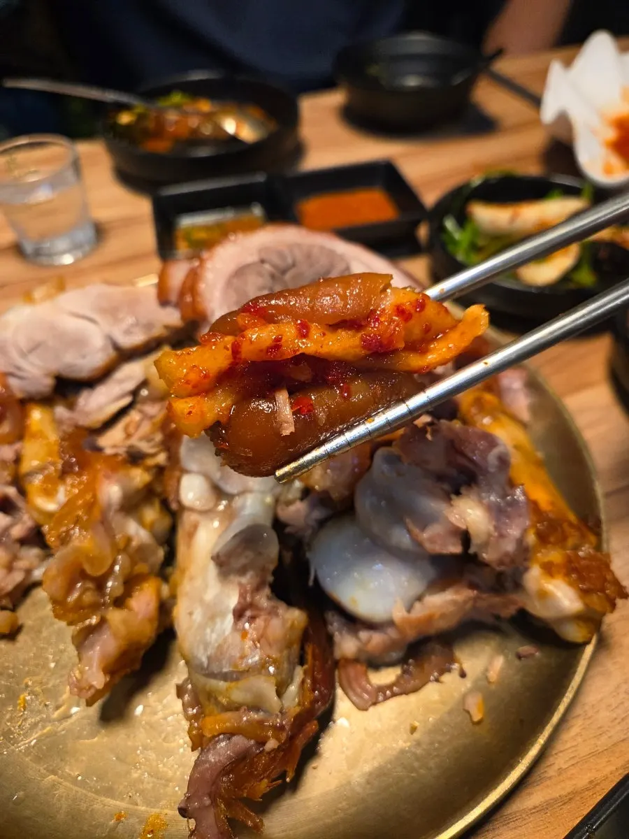 A piece of jokbal lifted with chopsticks