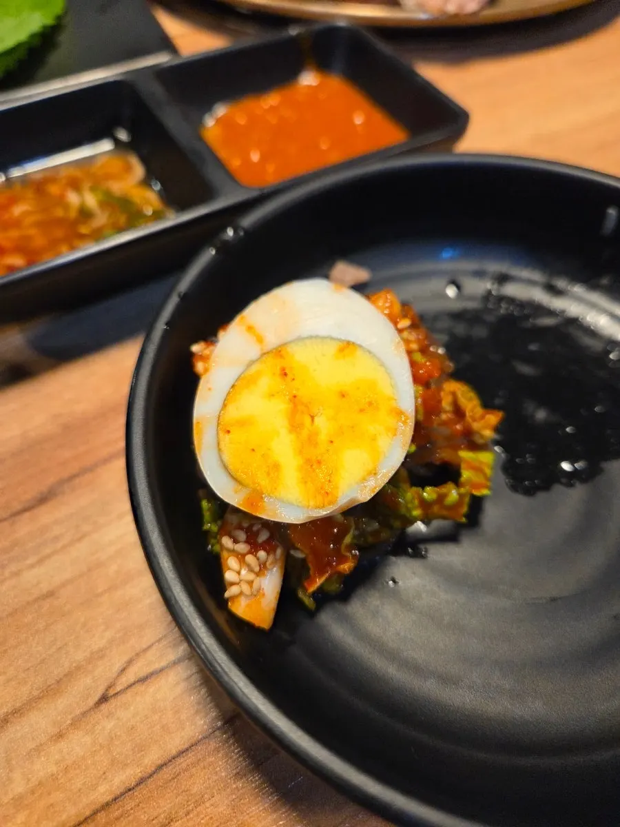 A wrap topped with jokbal and Jeju radish kimchi