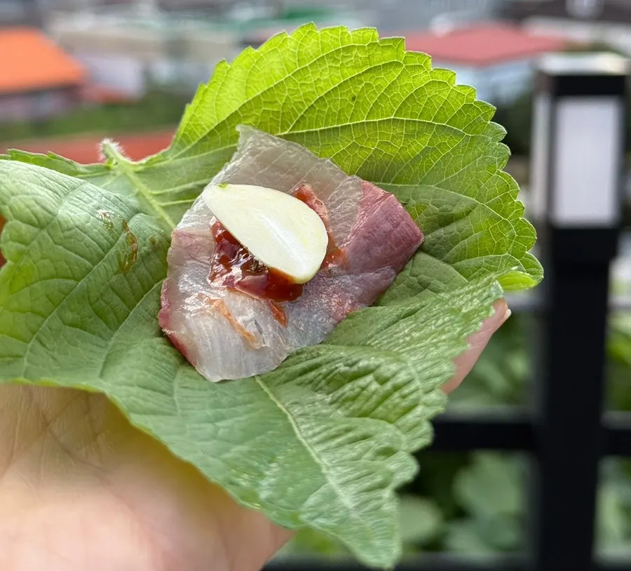 A slice of sashimi with perilla leaf and garlic