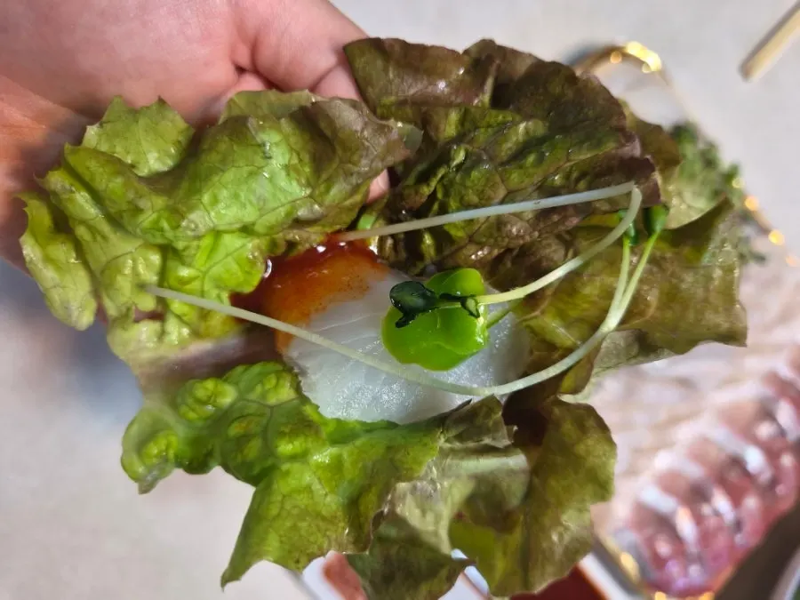 A piece of sashimi placed on a fresh lettuce leaf