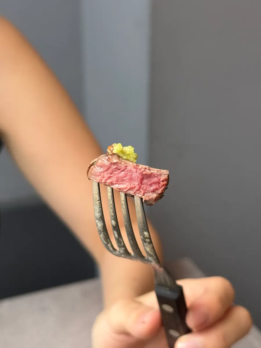 A piece of steak with sauce and wasabi