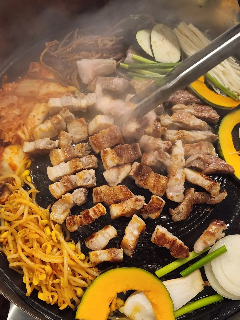 Thick fresh pork belly browning on the lid-shaped grill