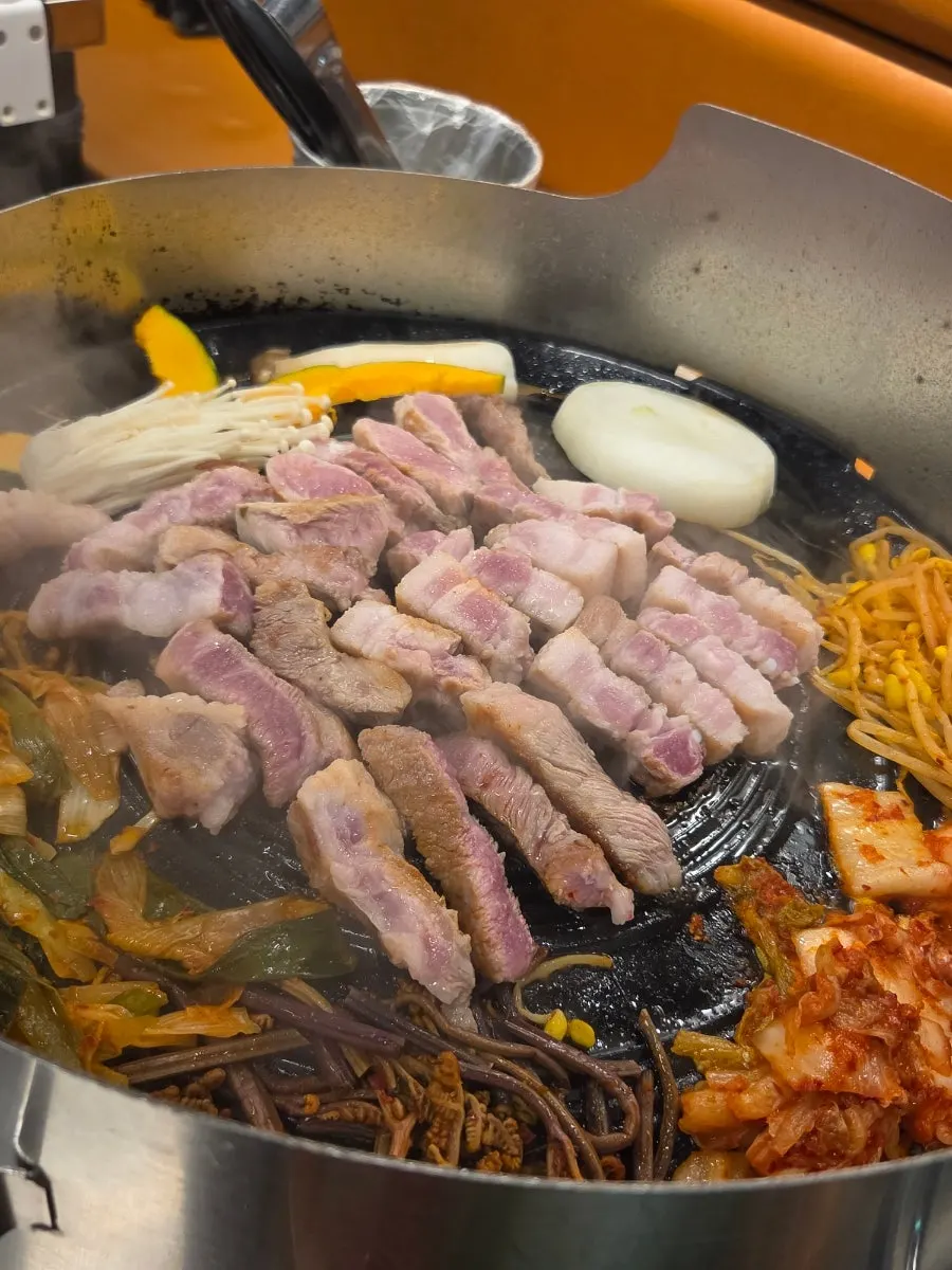 Pork belly and pork neck cooking on the cauldron-lid grill