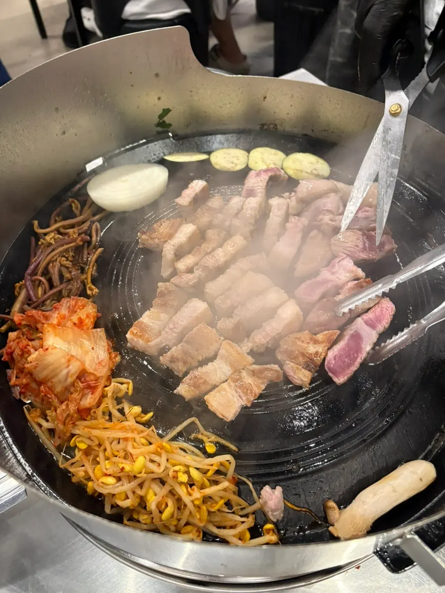 Kimchi, bean sprouts and bracken fern grilling on the cauldron lid