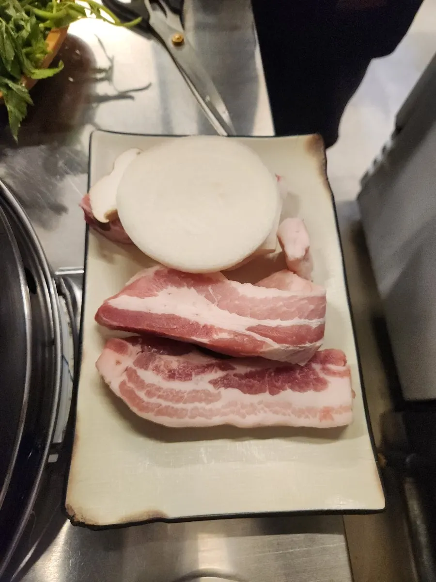 Thick fresh pork belly on the cauldron lid