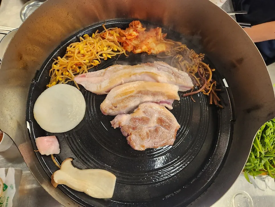 Staff member grilling pork belly with a splash guard set up