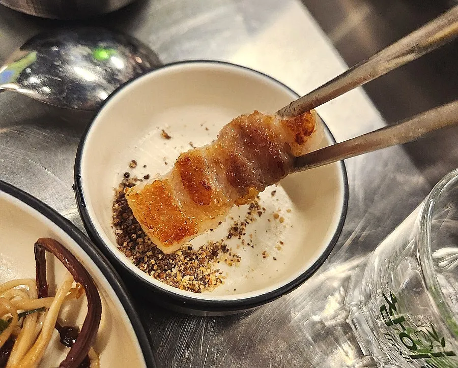 Golden-brown pork belly grilled on the cauldron lid