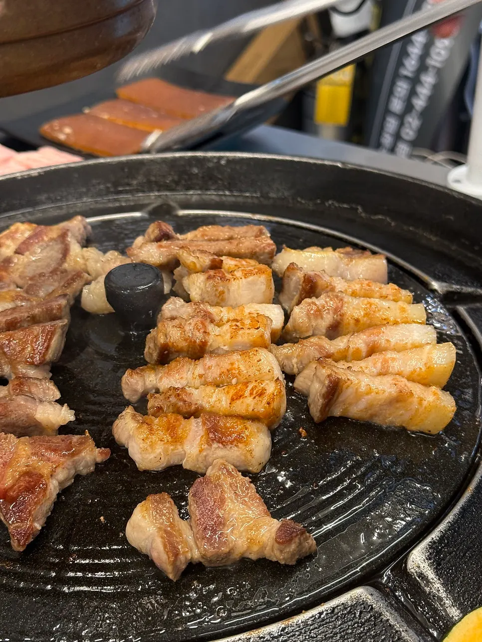 Close-up of pork belly grilling on the iron lid
