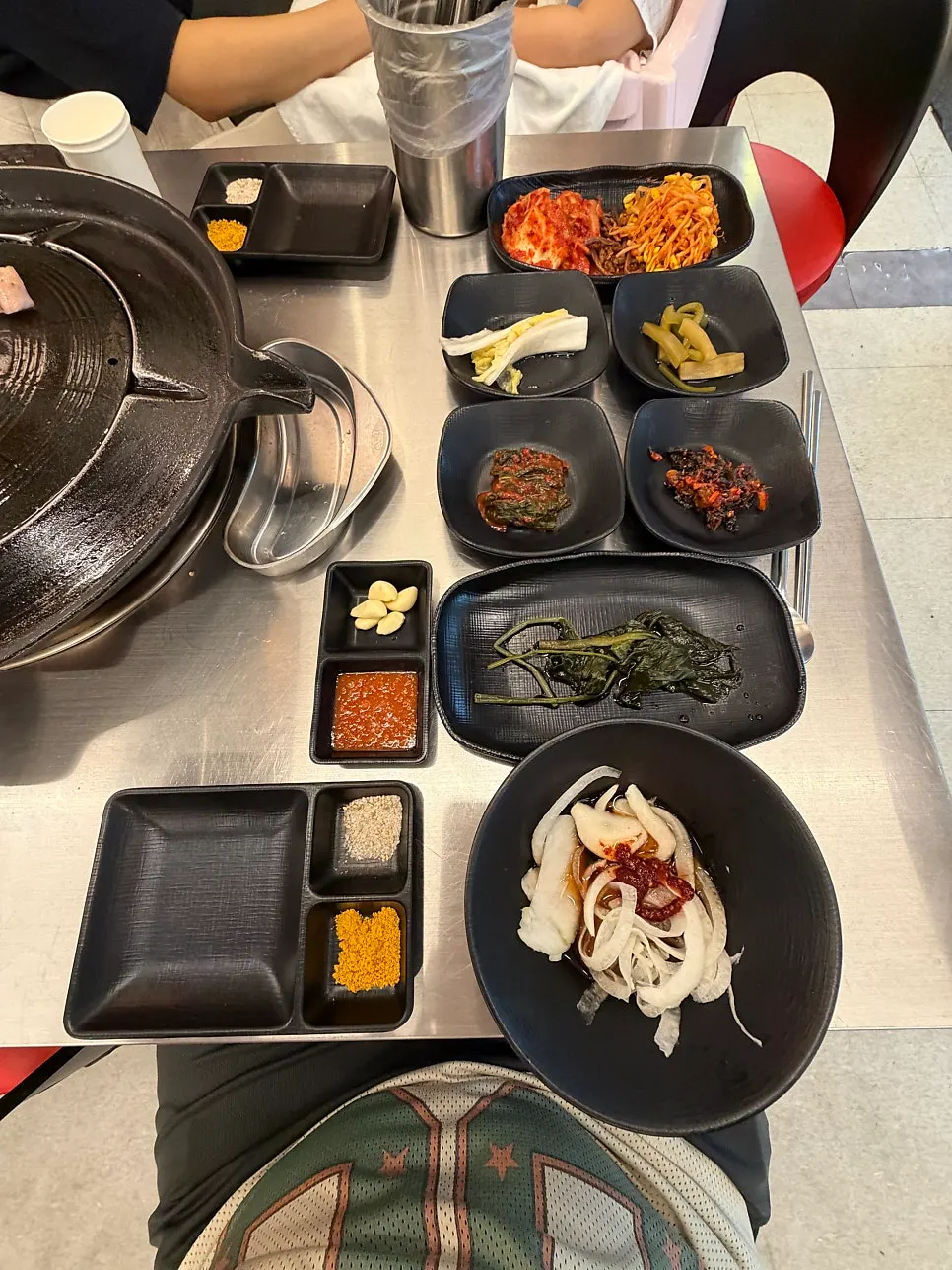 고기 굽기 전 솥뚜껑과 반찬이 놓인 테이블