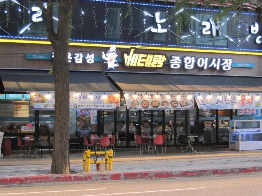 ป้ายร้าน Veteran General Fish Market สีเหลืองและที่นั่งเทอเรซ