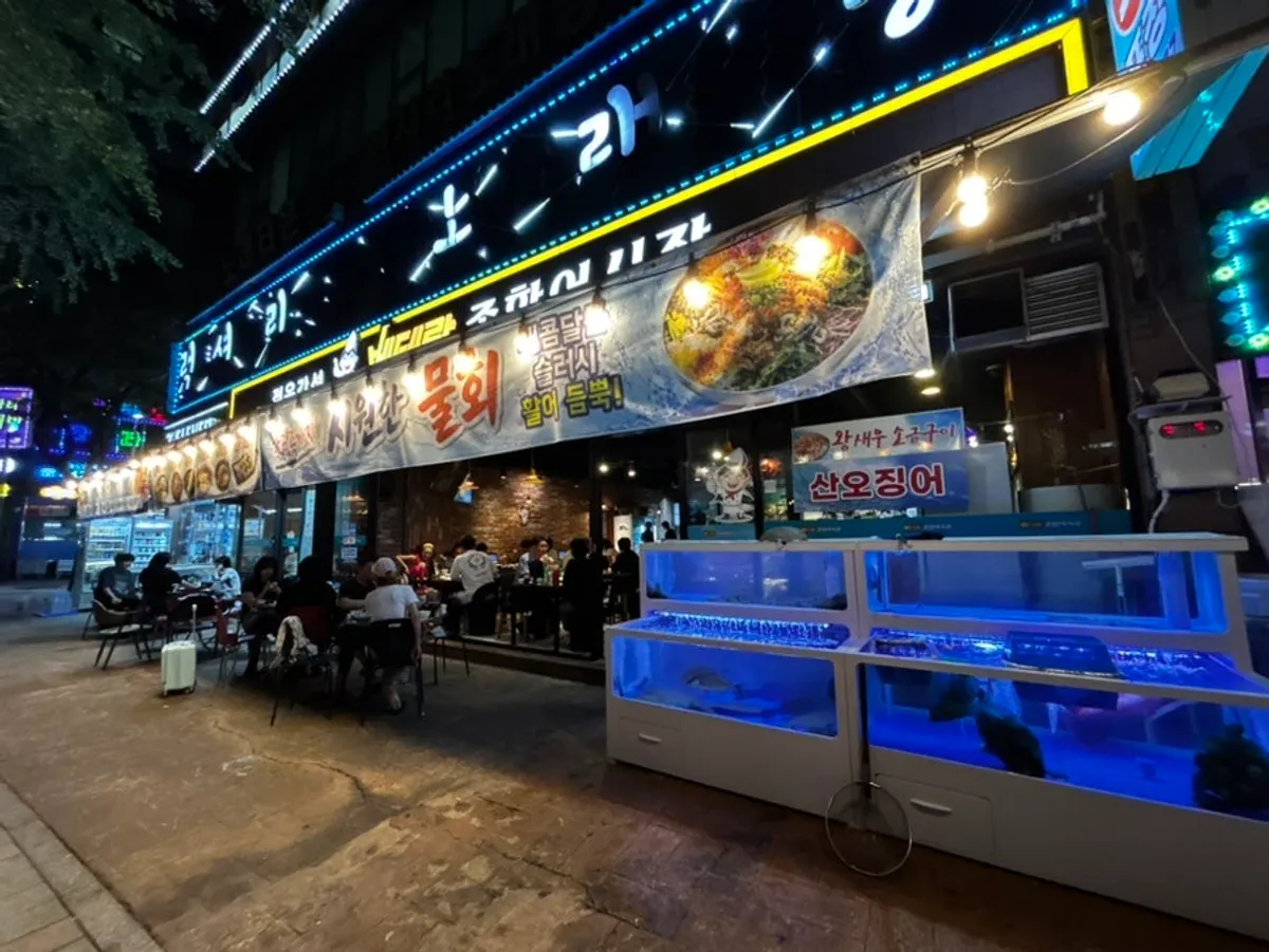 Fachada del restaurante en Guwol-dong con las puertas plegables abiertas y la terraza exterior